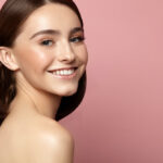 Beautiful smiling woman with clean skin, natural makeup and white teeth on a pink background