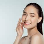 woman smiling while caressing her face